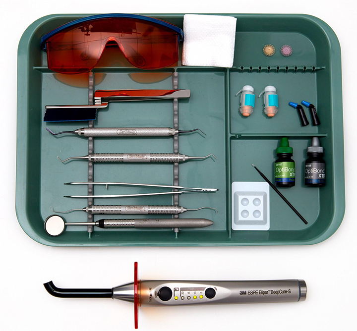 Essential restorative dental materials and examination gloves organized for chairside use.